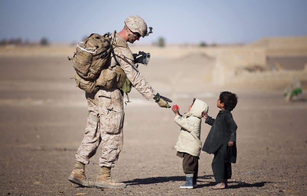 Soldat militaire tend la main à deux enfants